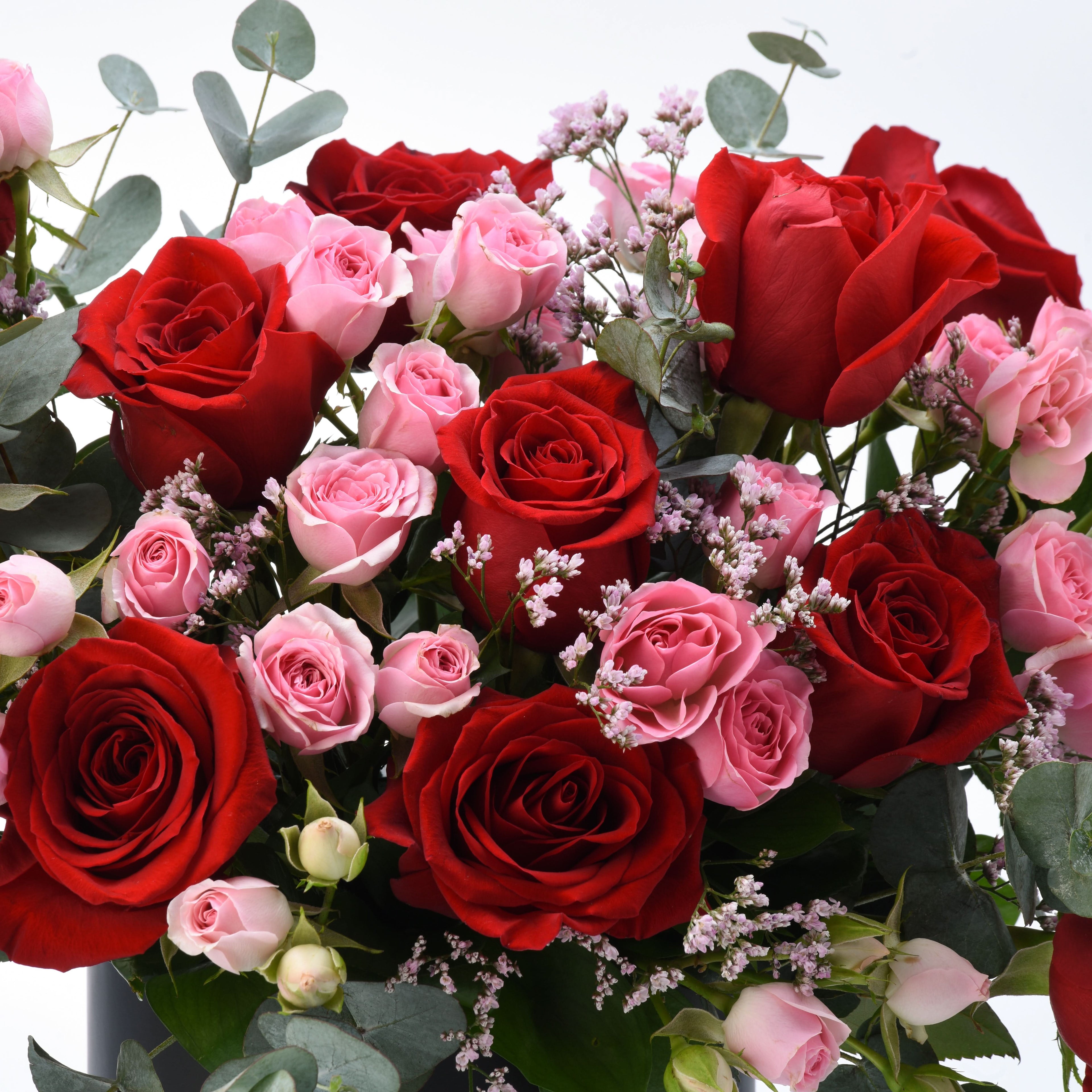Vibrant red and pink roses with eucalyptus, delicate baby’s breath, and lush greenery.