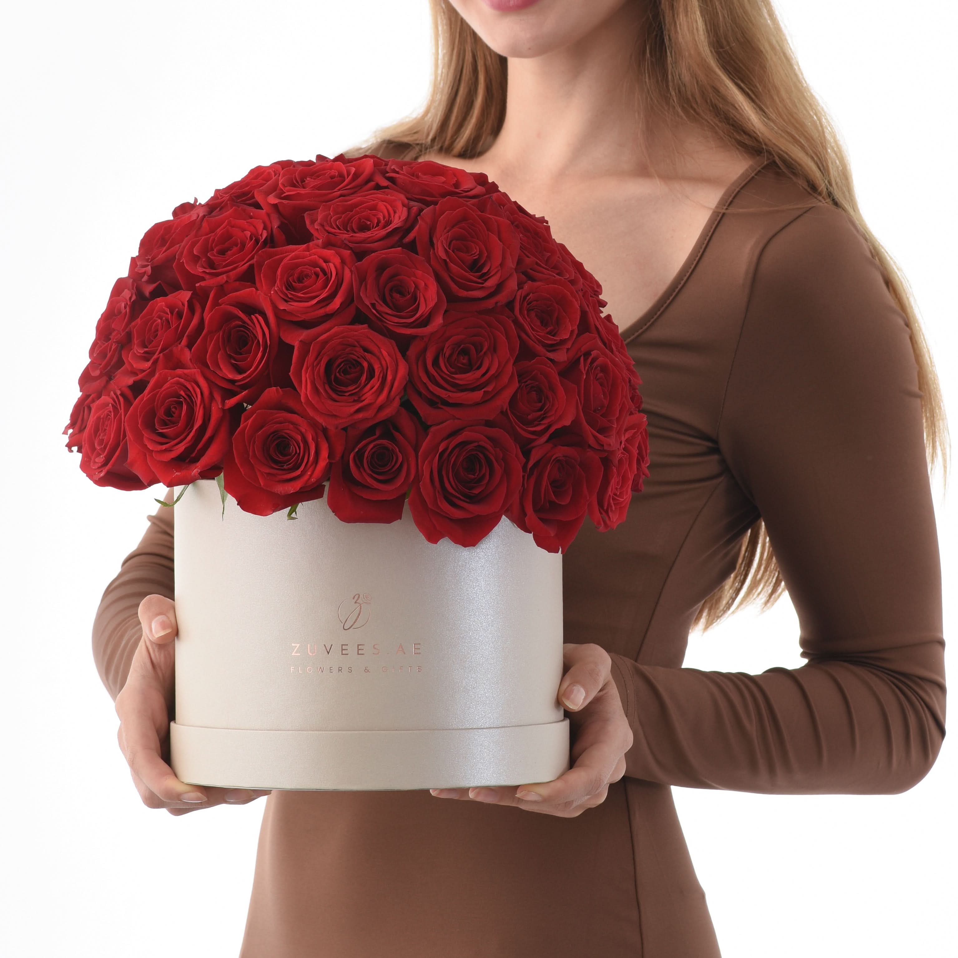 Woman holds luxurious white box overflowing with vibrant red roses.