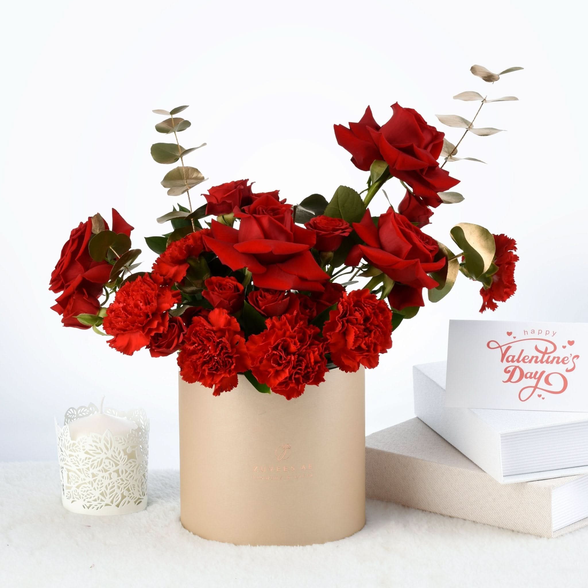 Vibrant red roses and carnations in beige cylinder vase, beside Valentine&
