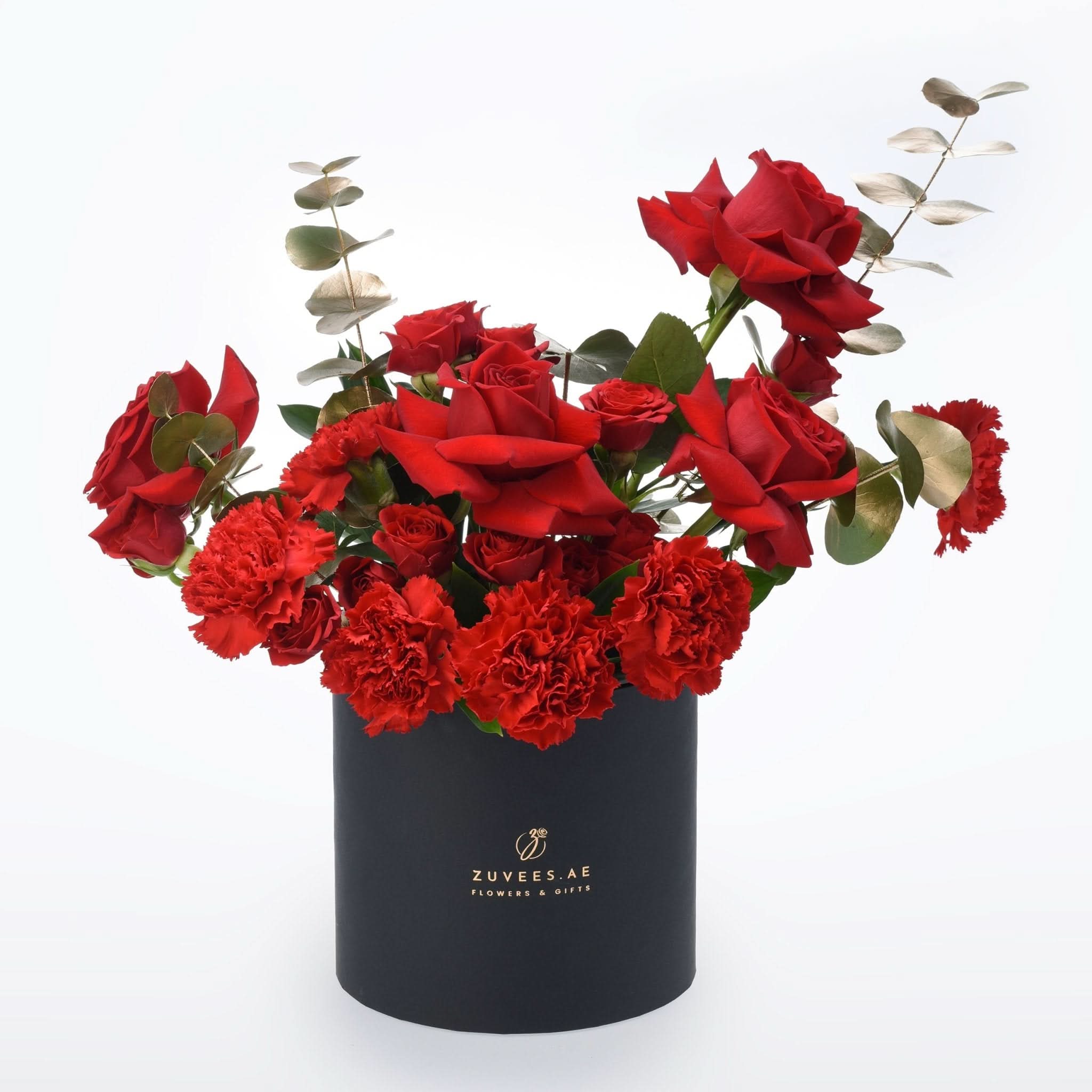 Vibrant red roses and carnations in sleek black cylindrical box.