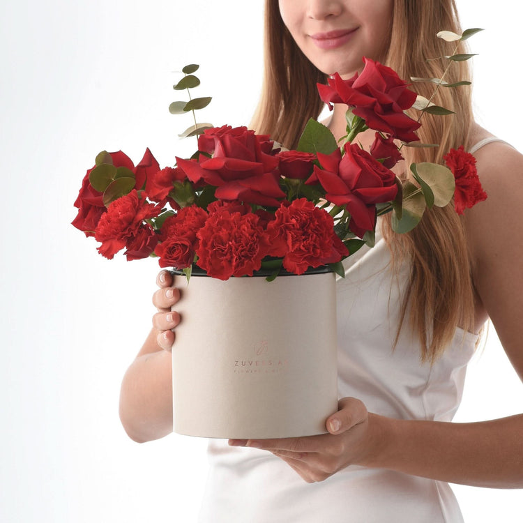 Elegant white box holds vibrant red roses and carnations, accented with eucalyptus.