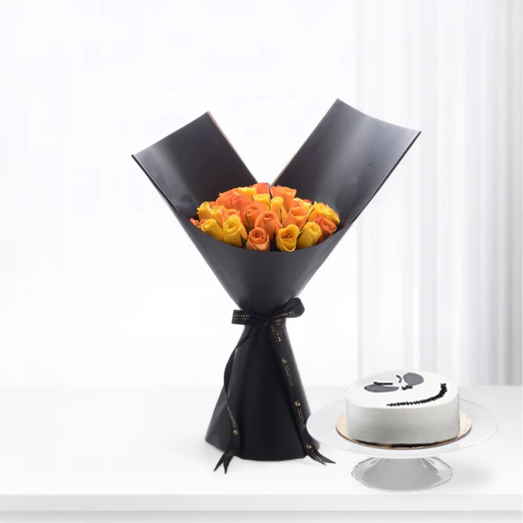 Vibrant orange-yellow roses in sleek black wrap, beside minimalist white cake.
