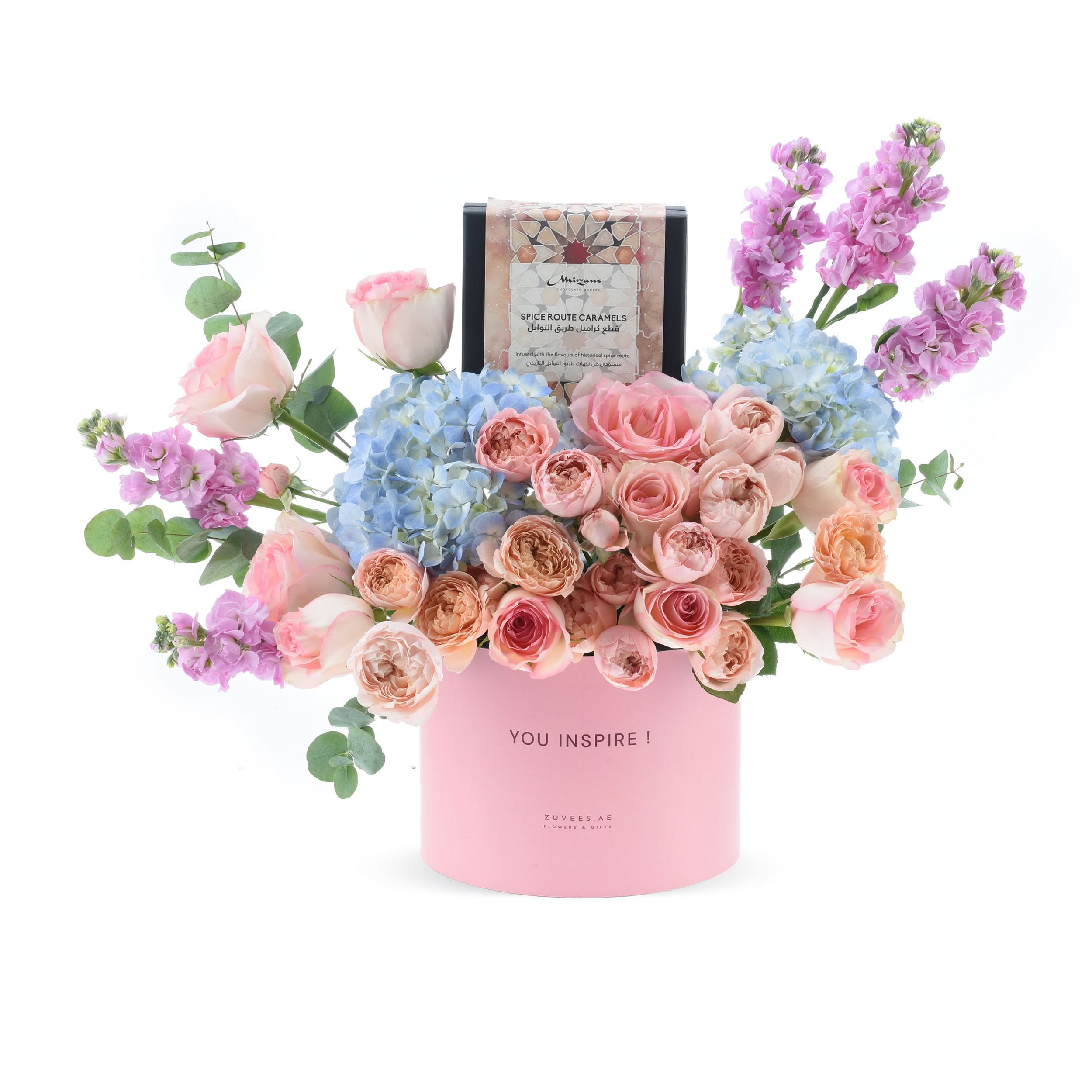 Pink floral arrangement with blue hydrangeas and roses, topped with "YOU INSPIRE!" gift box.