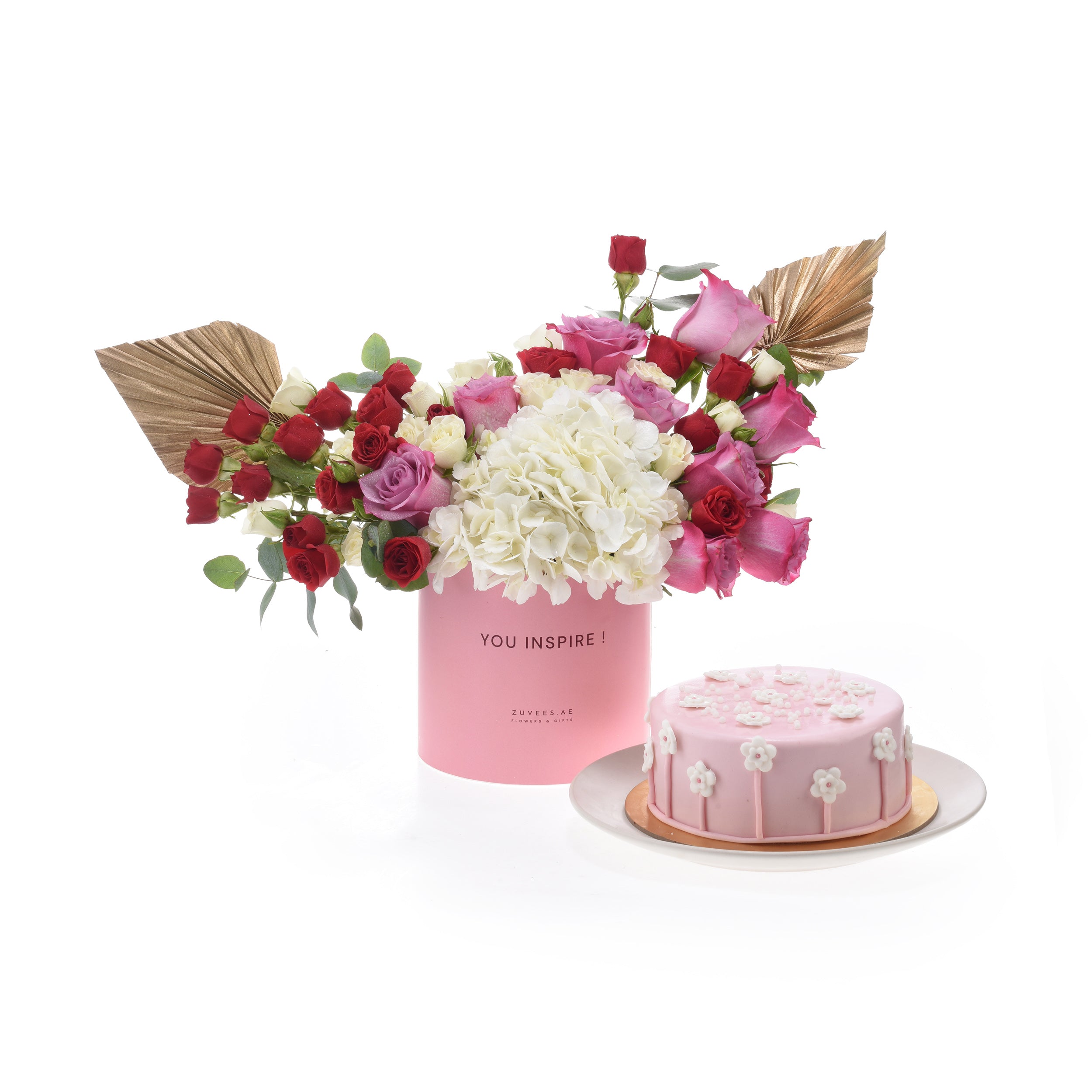 Pink floral arrangement with gold accents beside matching pink cake.