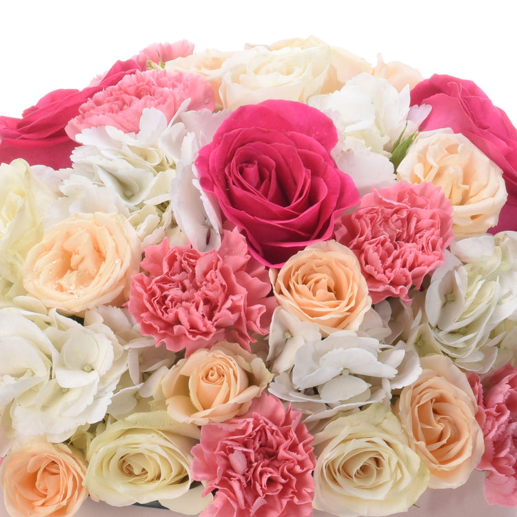 Vibrant pink, peach, and white roses and carnations in lush, dew-kissed bouquet.