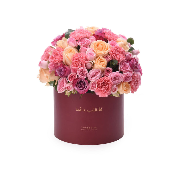 Luxury pink peach rose carnation bouquet in deep red Zuvees box, Arabic script elegance.