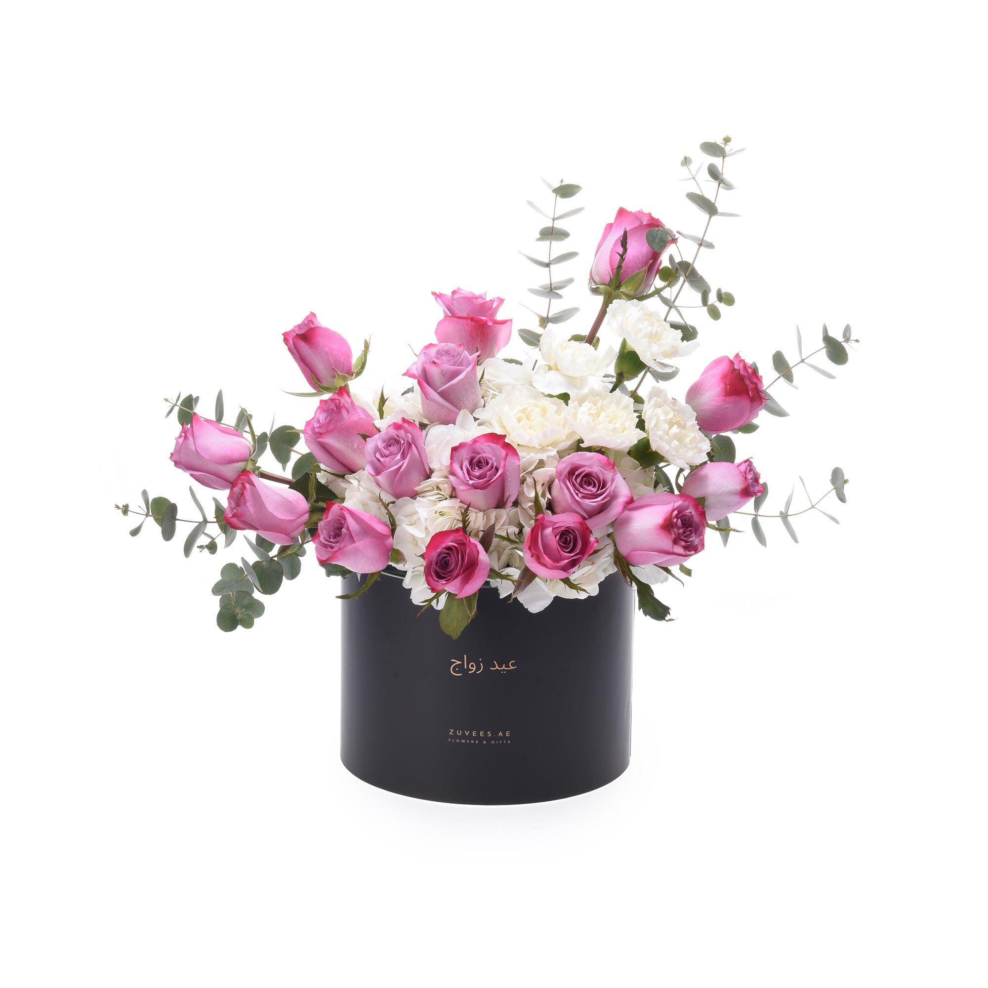Pink roses, white carnations, eucalyptus in sleek black box with gold Arabic text.