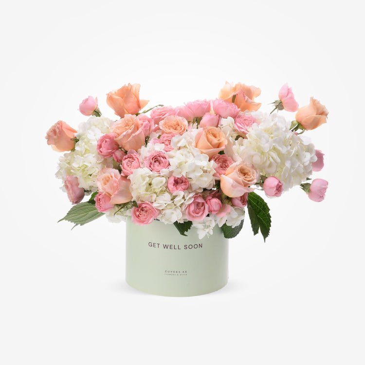 Pastel pink and peach roses with white hydrangeas in a mint "Get Well Soon" box.