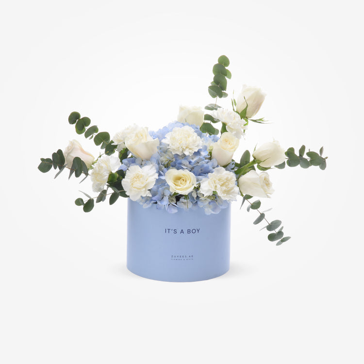 Soft blue box with white roses, hydrangeas, and eucalyptus reads “It’s a Boy.”