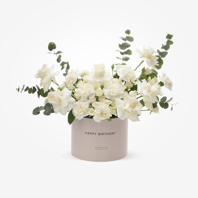 Elegant white roses and carnations in a blush "Happy Birthday" box with eucalyptus accents.