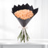 Soft peach roses in sleek black paper, tied with elegant white ribbon.