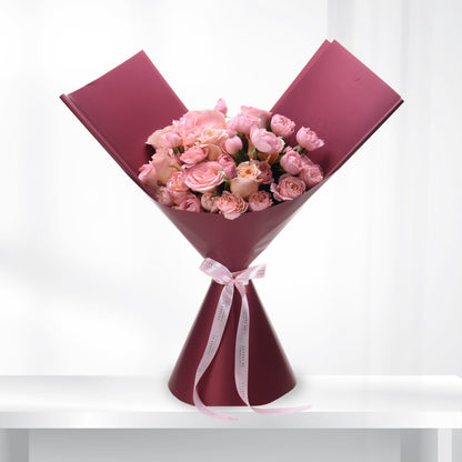 Soft pink roses in burgundy wrap, elegant ribbon bow, minimalist white background.