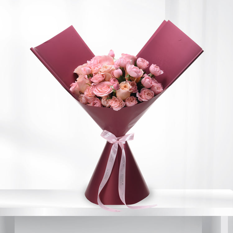 Soft pink roses in burgundy wrap, elegant ribbon bow, minimalist white background.