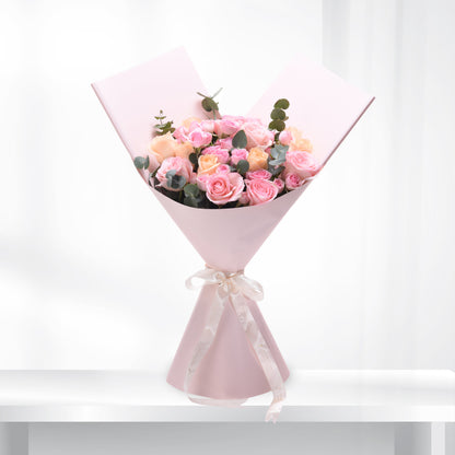 Soft pink roses and eucalyptus wrapped in pastel paper with elegant ribbon.