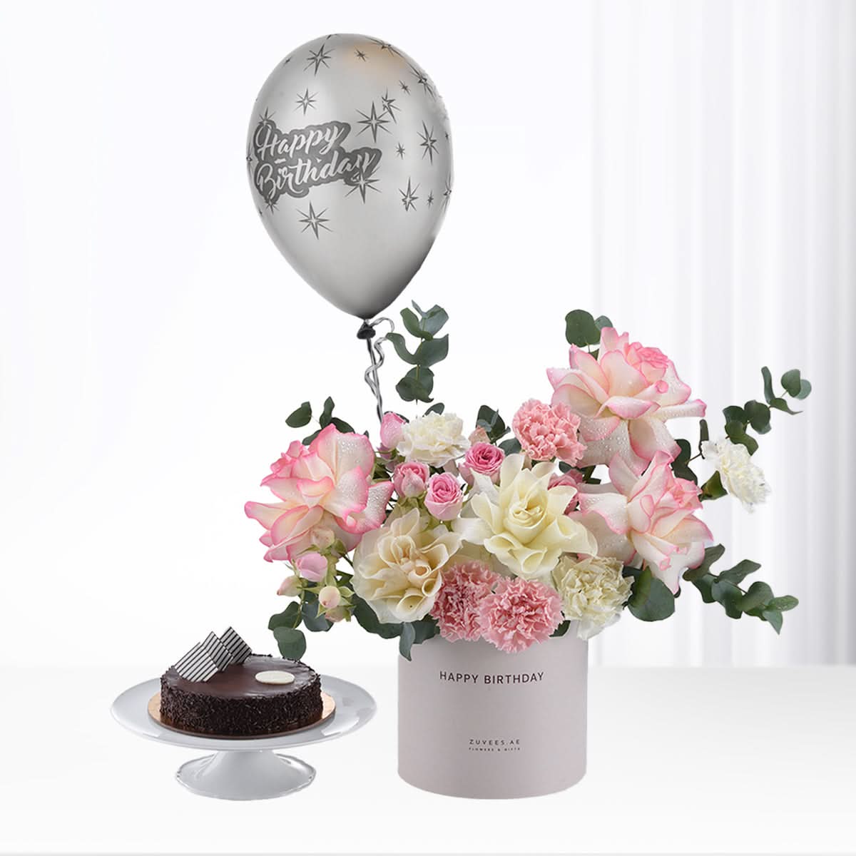 Silver balloon floats above pink-white roses and chocolate cake.