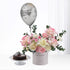 Silver balloon floats above pink-white roses and chocolate cake.