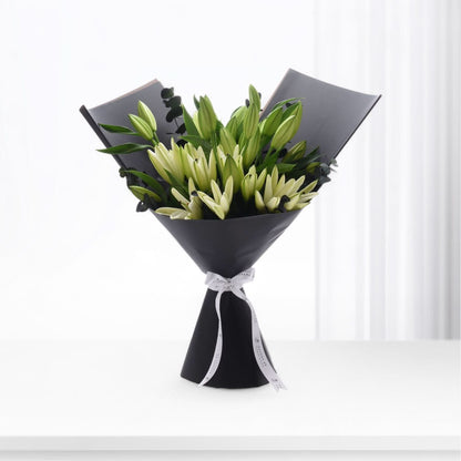 Elegant black-wrapped bouquet of creamy white lilies with green buds and eucalyptus.