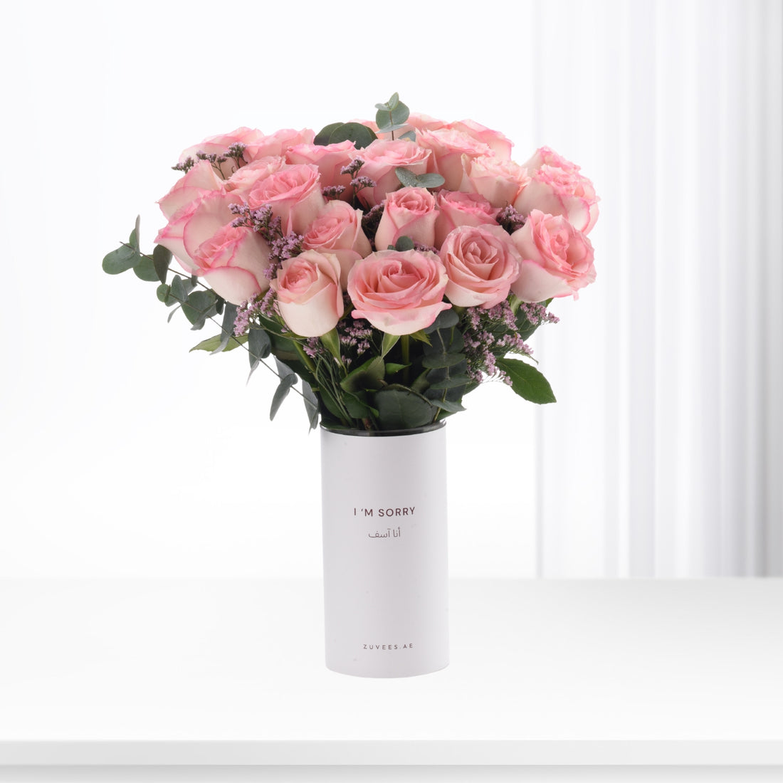 Soft pink roses in minimalist white vase with bilingual apology message.
