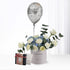 Silver balloon floats above white roses and blue hydrangeas in a birthday-themed vase.