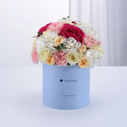 Pastel blue box holds vibrant pink, white, and peach roses and carnations.