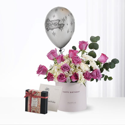 Silver balloon floats above pink roses and white hydrangeas in branded box.