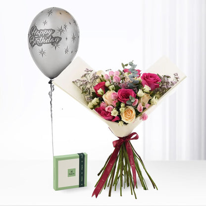 Silver "Happy Birthday" balloon floats beside vibrant rose bouquet with burgundy ribbon and green gift box.