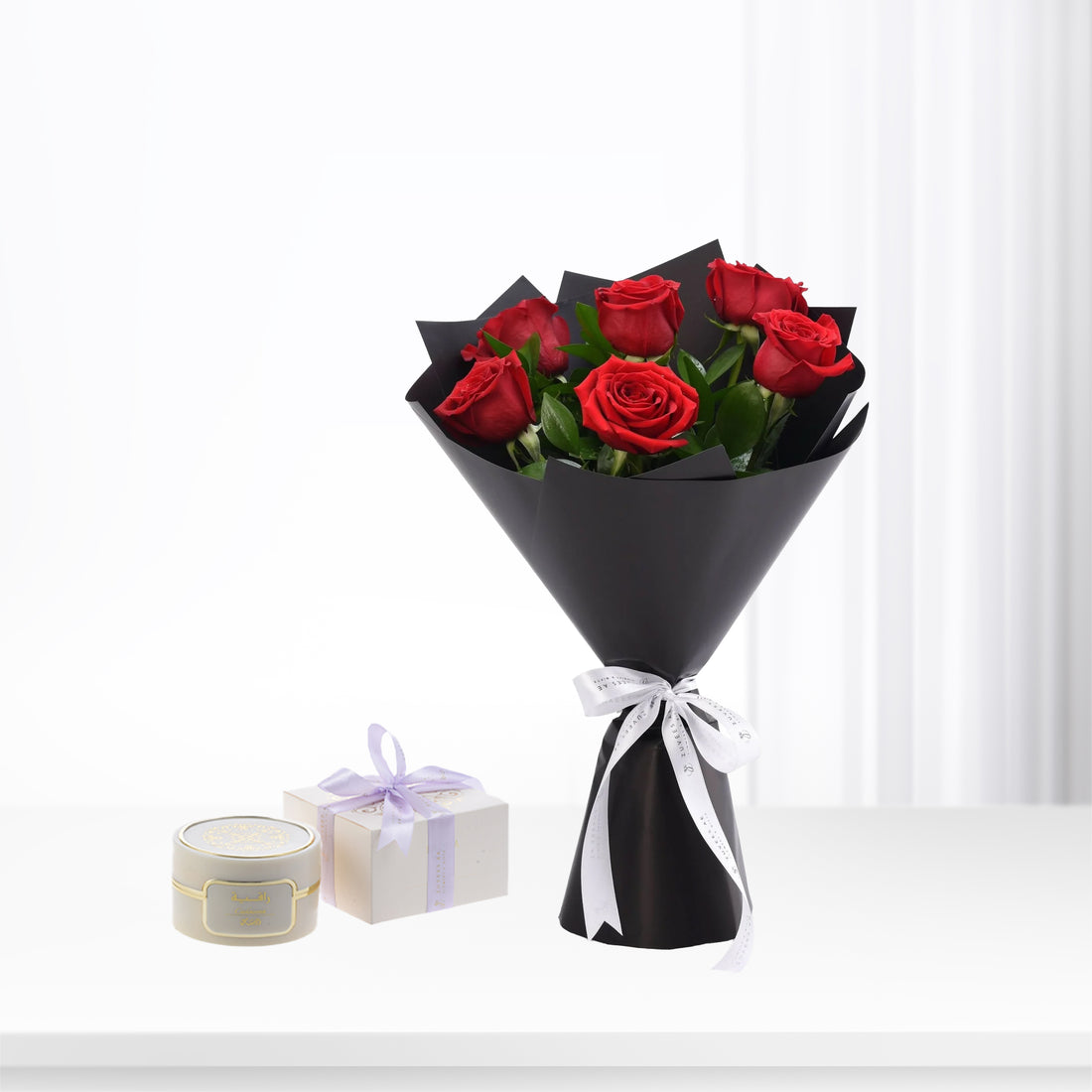Vibrant red roses in sleek black wrap, white ribbon, paired with luxury gift boxes.