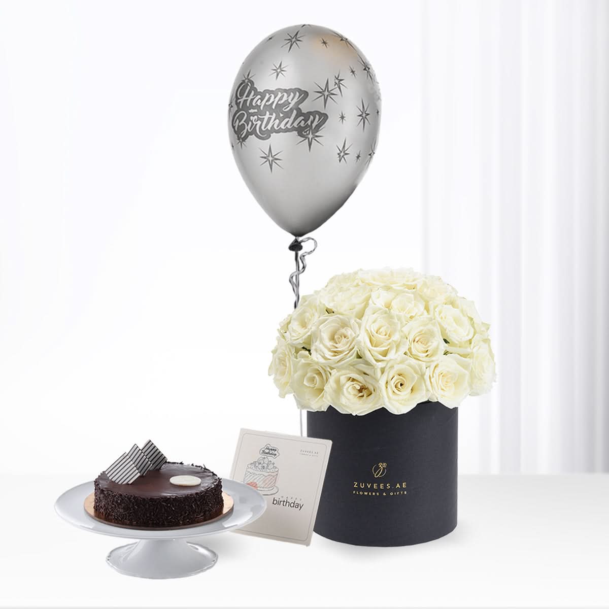 Silver balloon, white roses in black box, chocolate cake—birthday gift set.