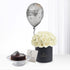 Silver balloon, white roses in black box, chocolate cake—birthday gift set.