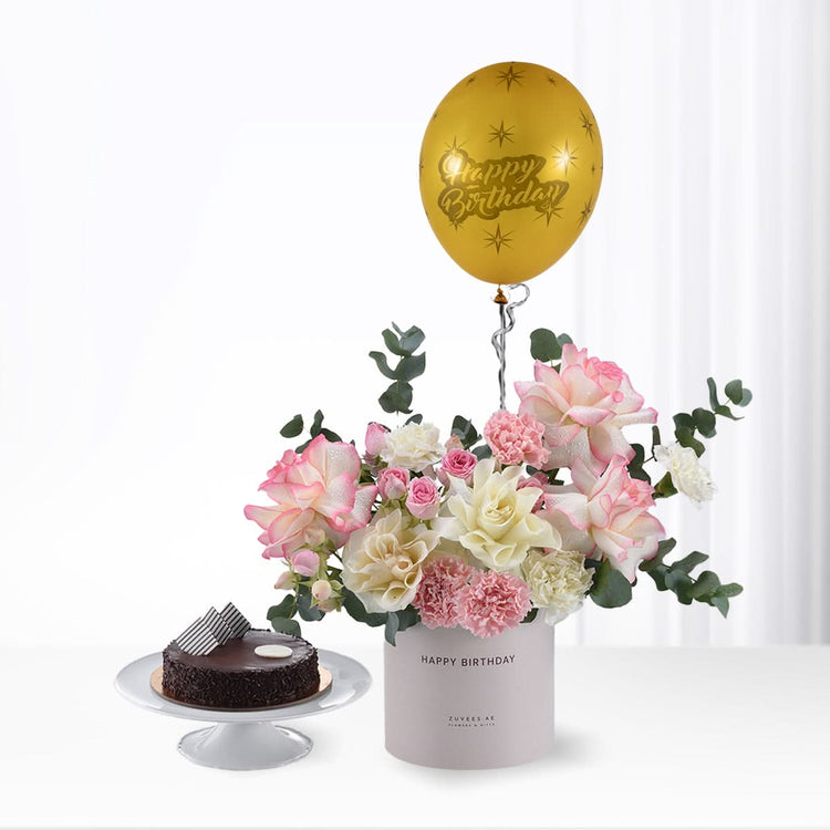 Golden balloon floats above pink-white roses and chocolate cake.