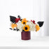 Bold sunflowers, white hydrangeas, and red roses in deep burgundy vase.