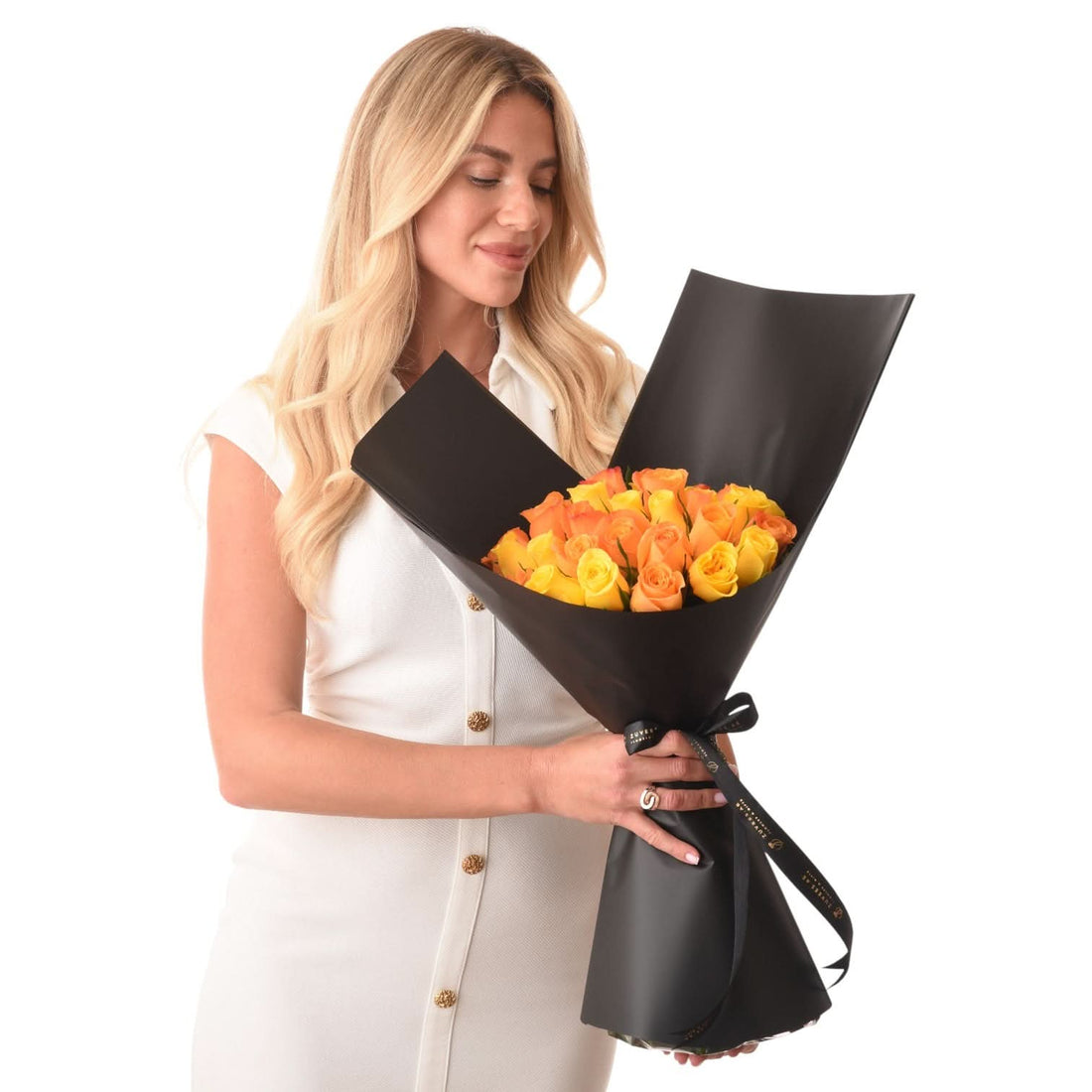 Woman holds elegant black-wrapped bouquet of vibrant yellow-orange roses.