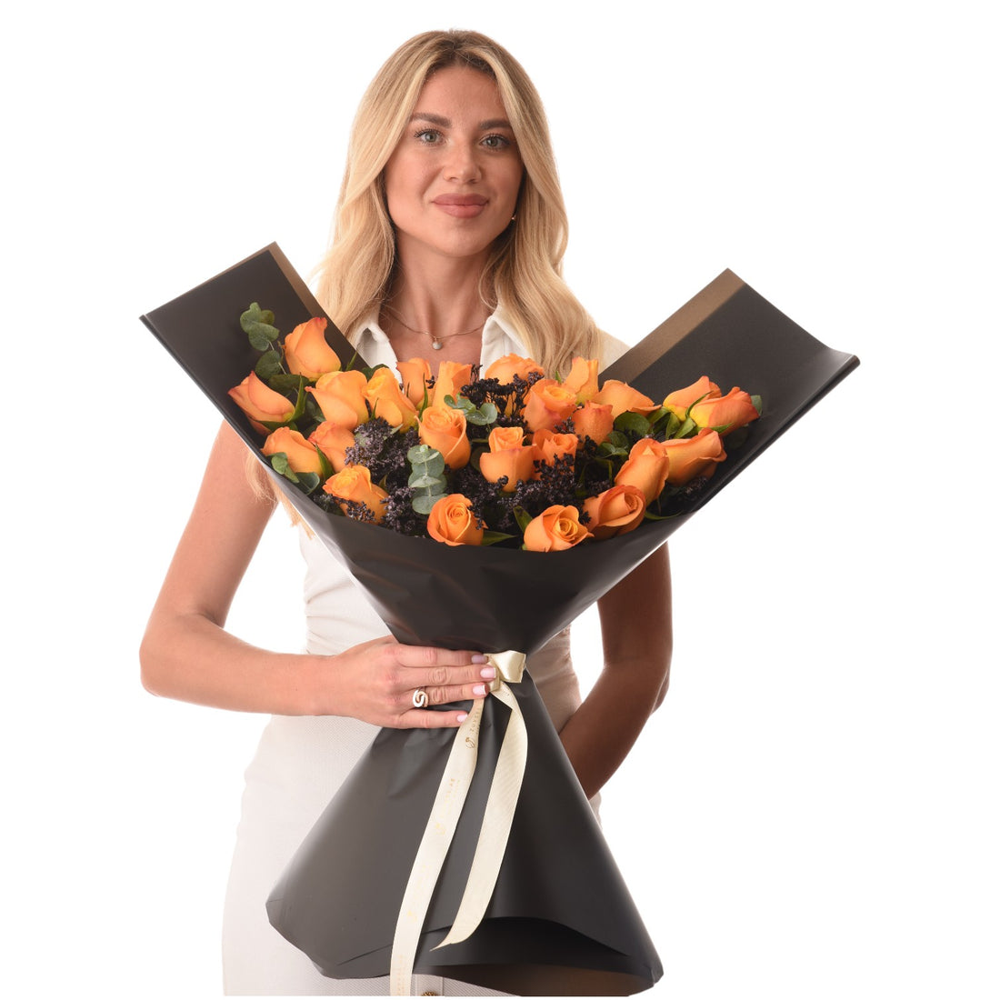 Vibrant orange roses in sleek black wrap, accented with dark filler and cream ribbon, held elegantly.