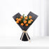 Vibrant orange roses elegantly wrapped in matte black paper with cream ribbon bow.