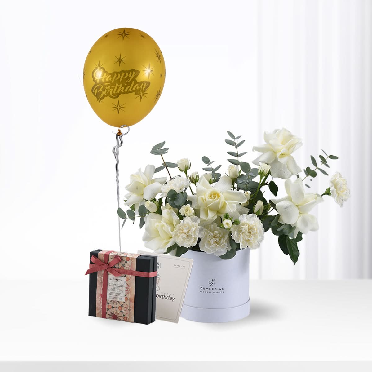 Golden balloon, white roses, and gift box celebrate birthday elegantly.