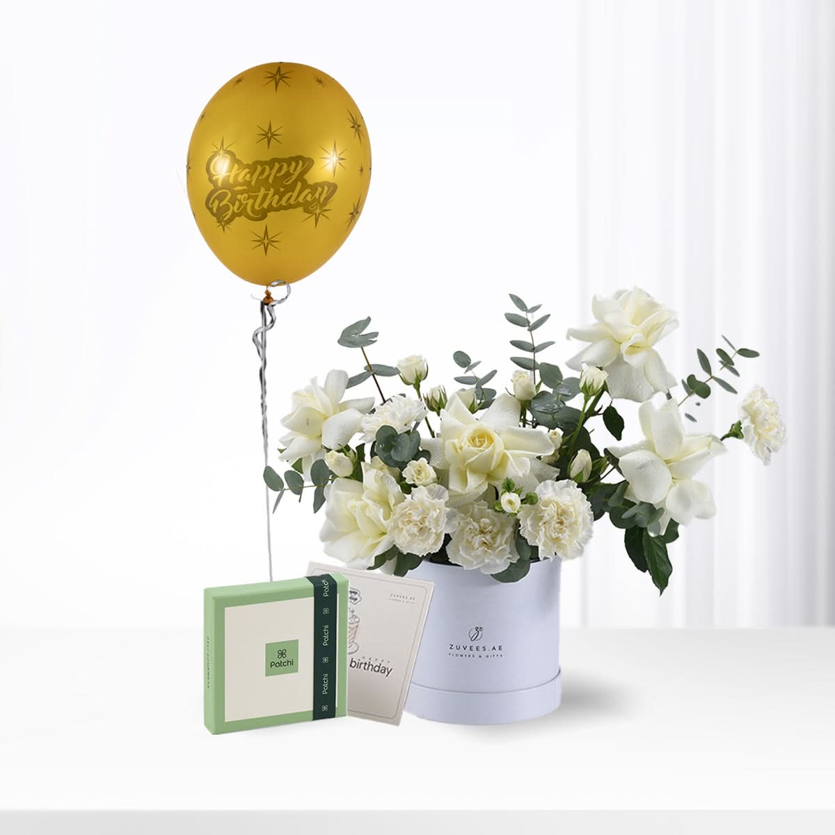 Golden balloon, white roses, greenery, and Patchi chocolates in elegant birthday gift arrangement.