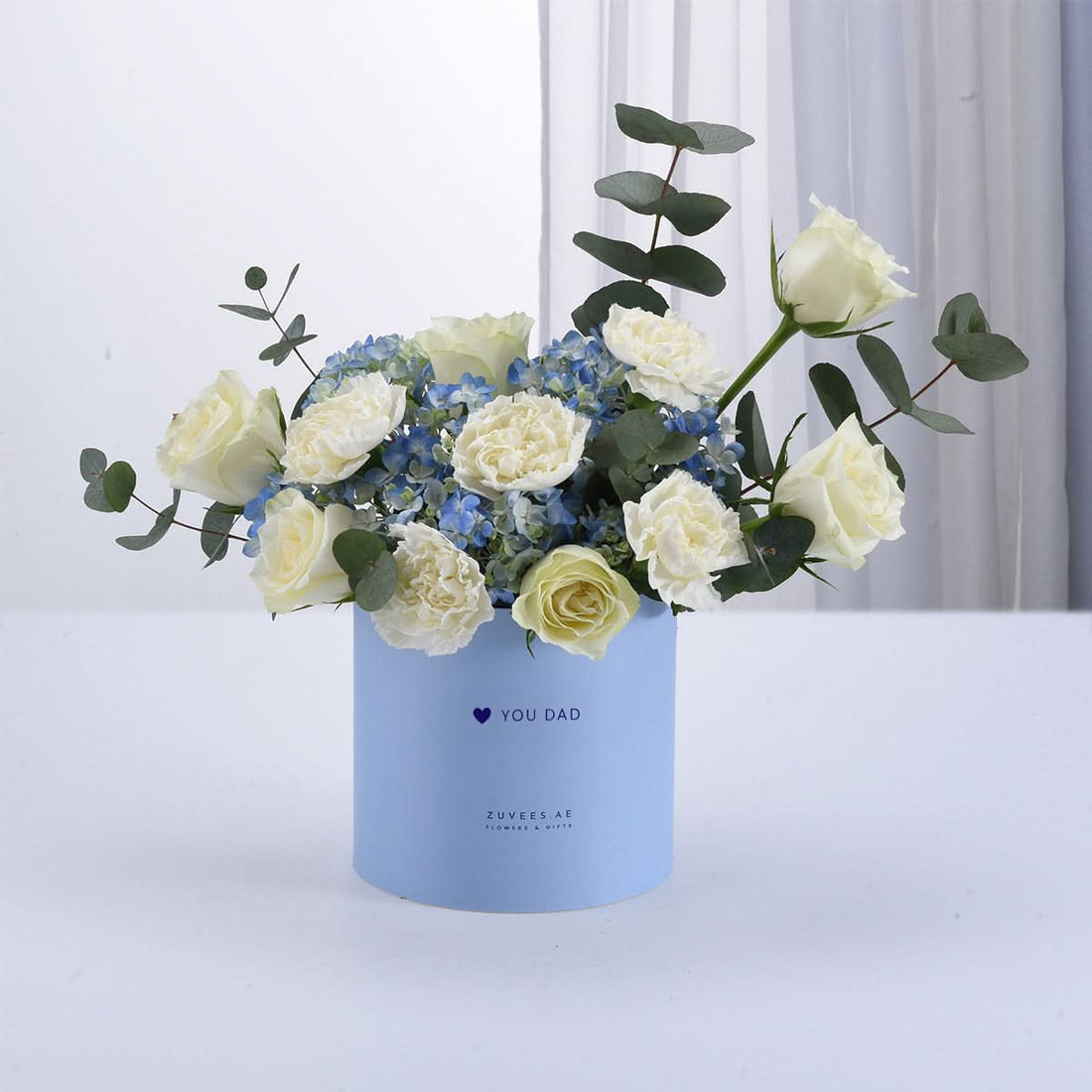 Soft blue box holds creamy roses, hydrangeas, and eucalyptus—perfect Father’s Day gift.