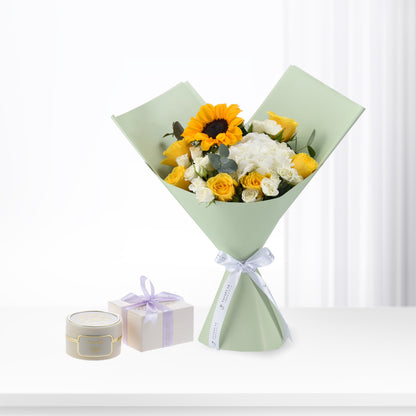 Sunflower, yellow, and white rose bouquet in mint wrap with lavender ribbon, beside gift boxes.
