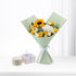 Sunflower, yellow, and white rose bouquet in mint wrap with lavender ribbon, beside gift boxes.