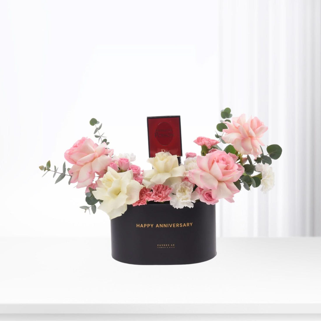 Black "Happy Anniversary" box with pink/white roses, eucalyptus, and Dior perfume gift.