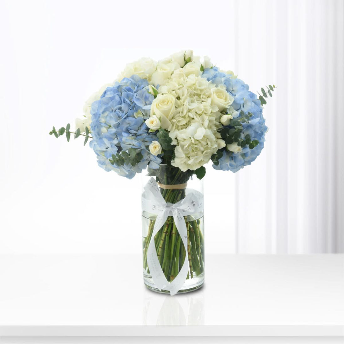 Blue hydrangeas and ivory roses arranged in a vase, Zuvees flower delivery UAE