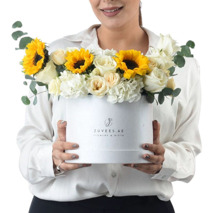 White box holds vibrant sunflowers and creamy roses, elegantly presented.