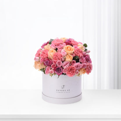 Pink and peach roses, carnations in white hat box.