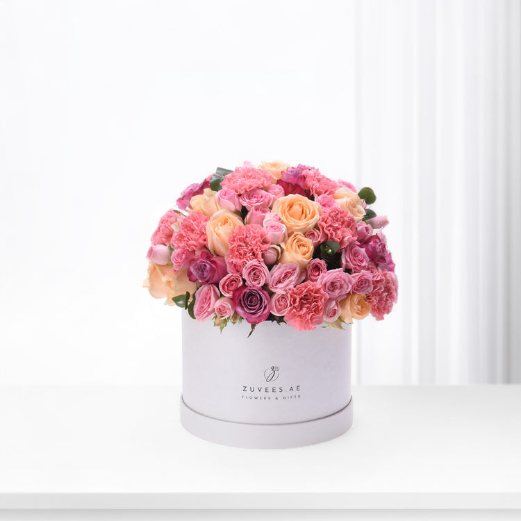 Pink and peach roses, carnations in white hat box.