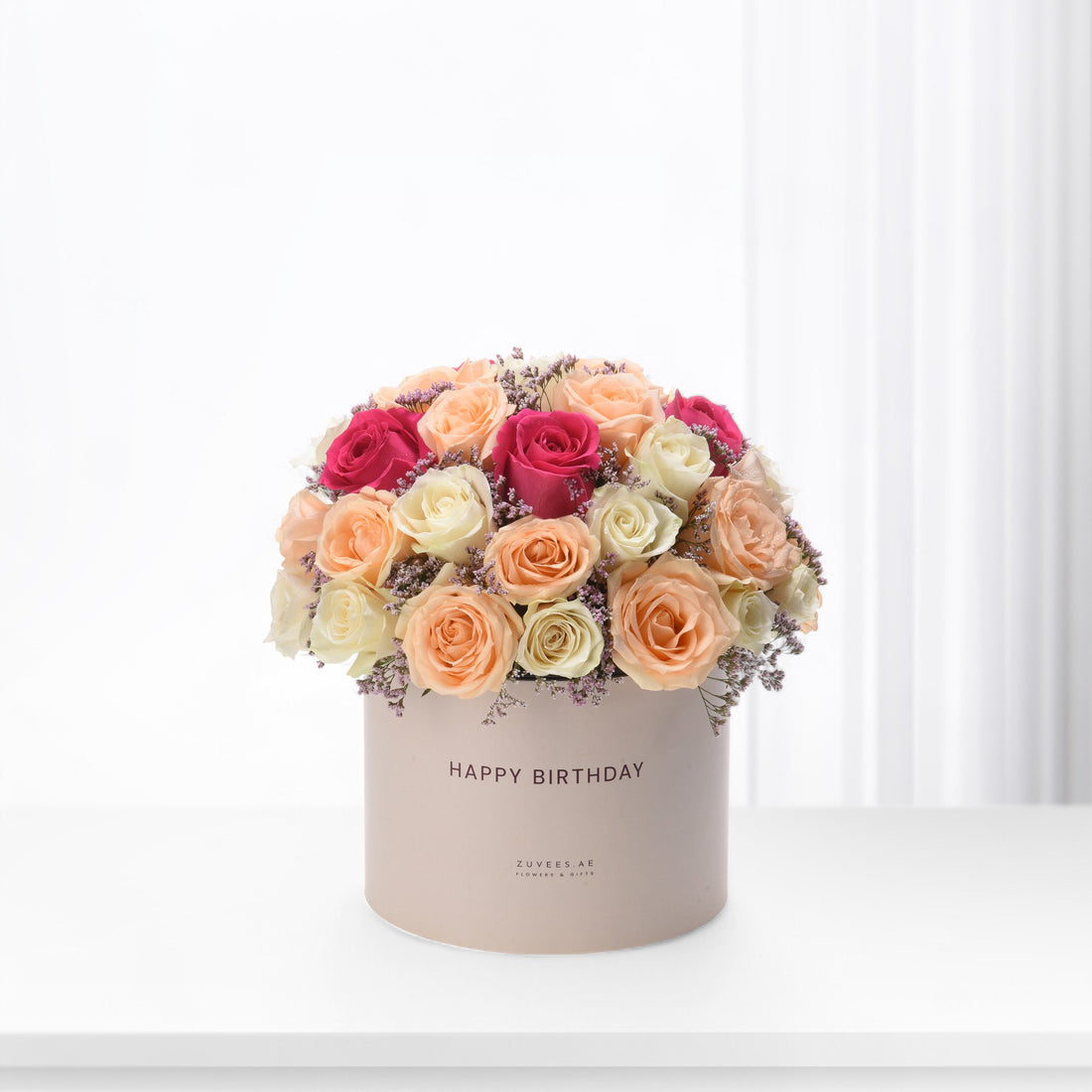 Pastel pink, peach, and magenta roses in a beige "Happy Birthday" box.
