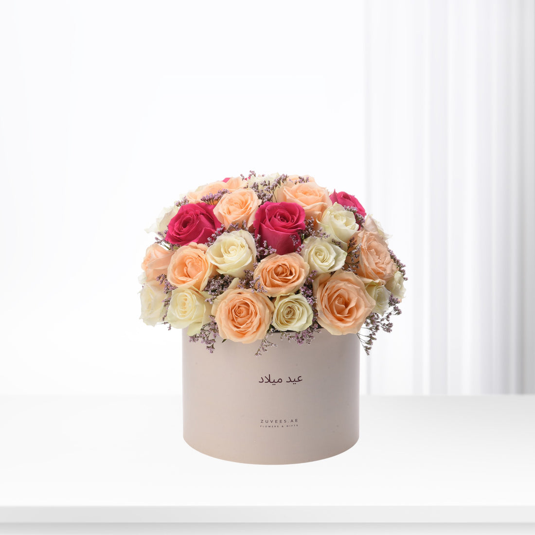 Pastel pink, peach, and magenta roses in blush box with "عيد ميلاد" text.