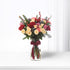 Vibrant red, pink, and cream roses with pinecones and berries in clear glass vase.