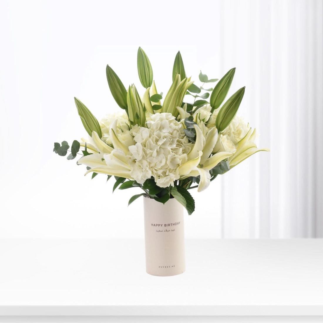 Elegant white lilies, hydrangeas, and buds in minimalist vase with "Happy Birthday" text.