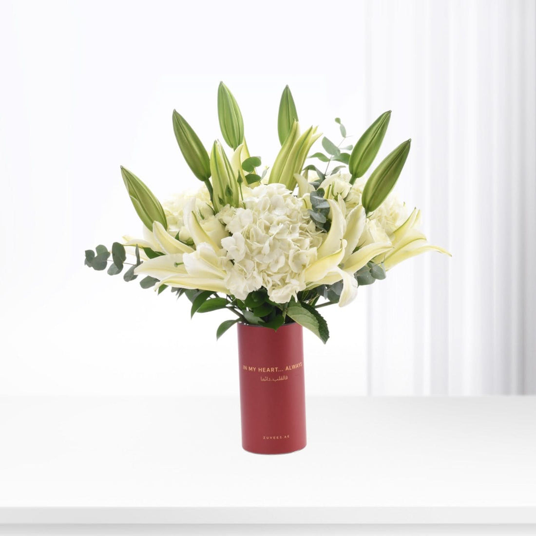 Elegant white lilies and hydrangeas in a bold red vase with heartfelt message.