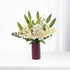 Elegant white lilies and hydrangeas in burgundy vase against soft white backdrop.